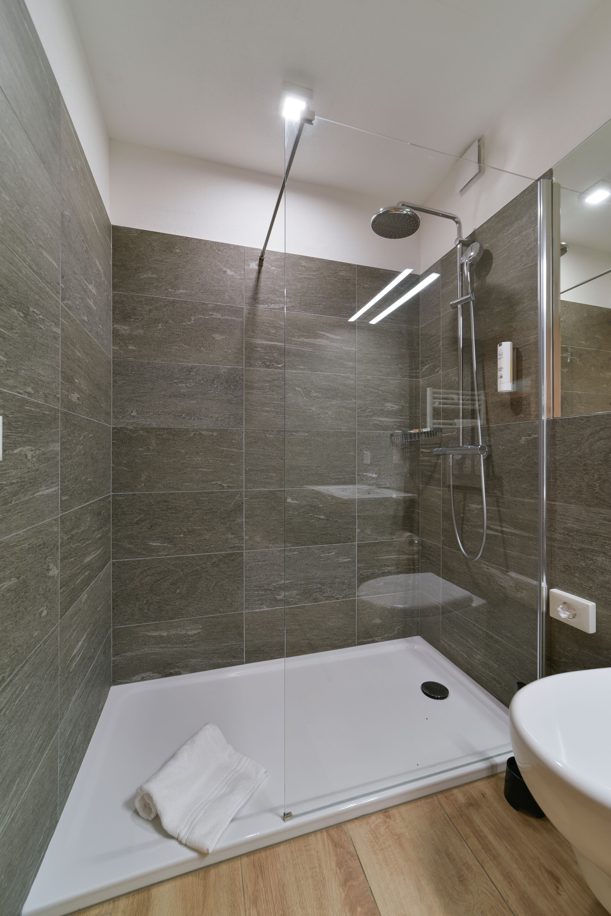 Une salle de bain moderne avec une douche à parois de verre, une baignoire blanche et un grand miroir.