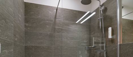 A modern bathroom with a glass-enclosed shower, a white bathtub, and a large mirror.