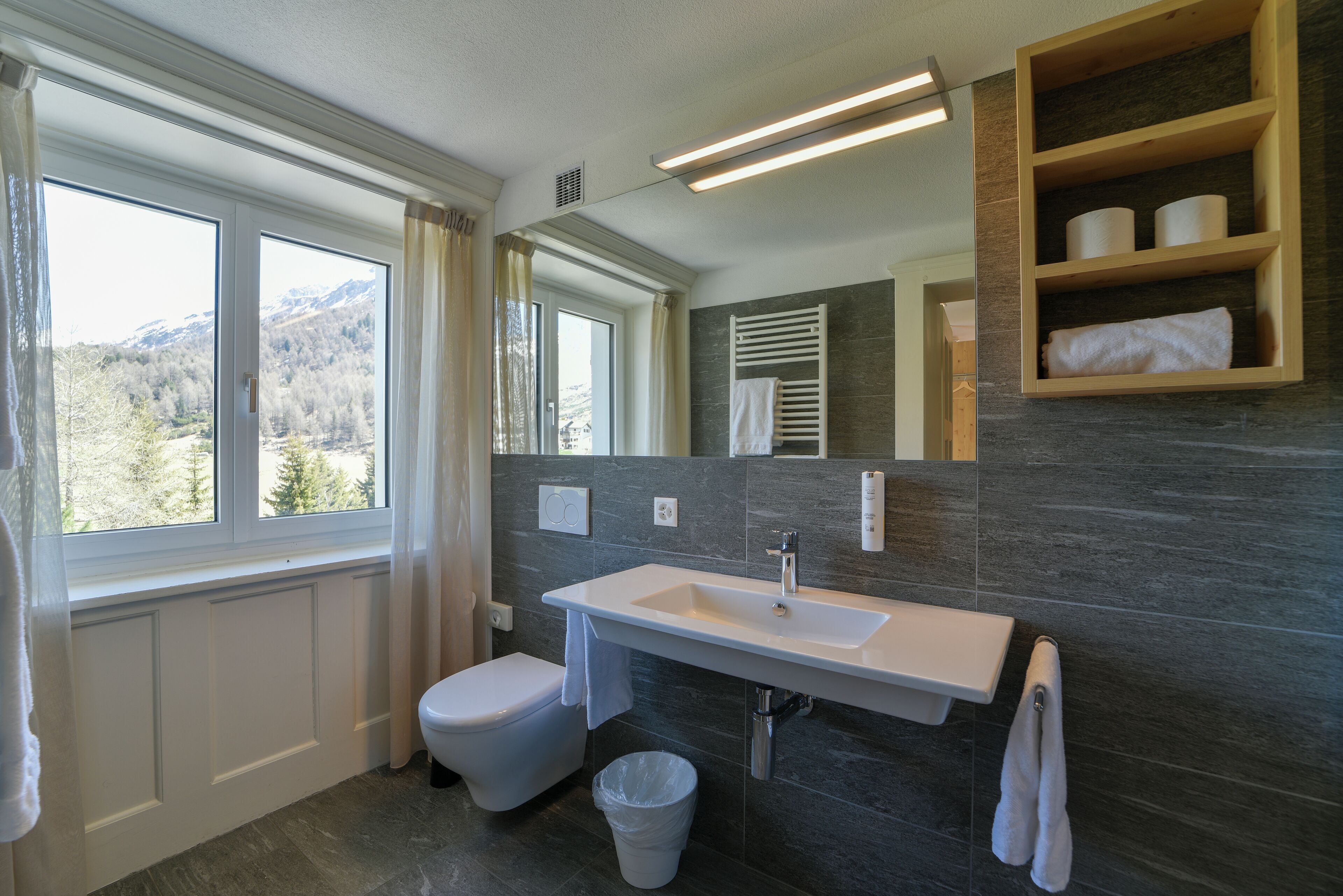 Un bagno moderno con un'ampia finestra, un lavandino bianco e un porta asciugamani a muro.