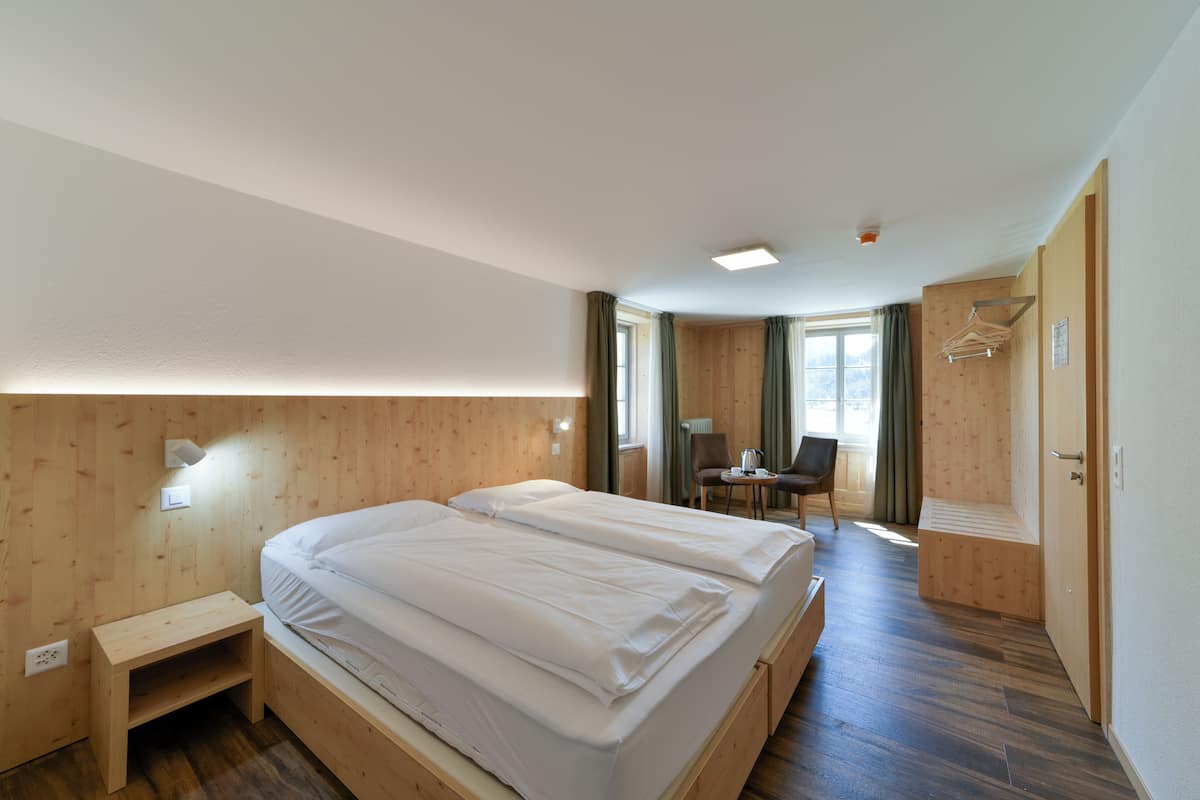 Une chambre d’hôtel avec deux lits, un bureau, une chaise et un petit coin salon.