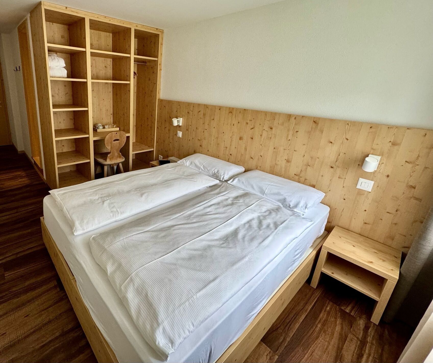 A bedroom with a wooden bed, a wooden wardrobe, and a small wooden table.