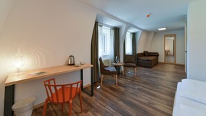 Een moderne hotelkamer met een houten bureau, een oranje stoel, een bruine bank en een witte divan.