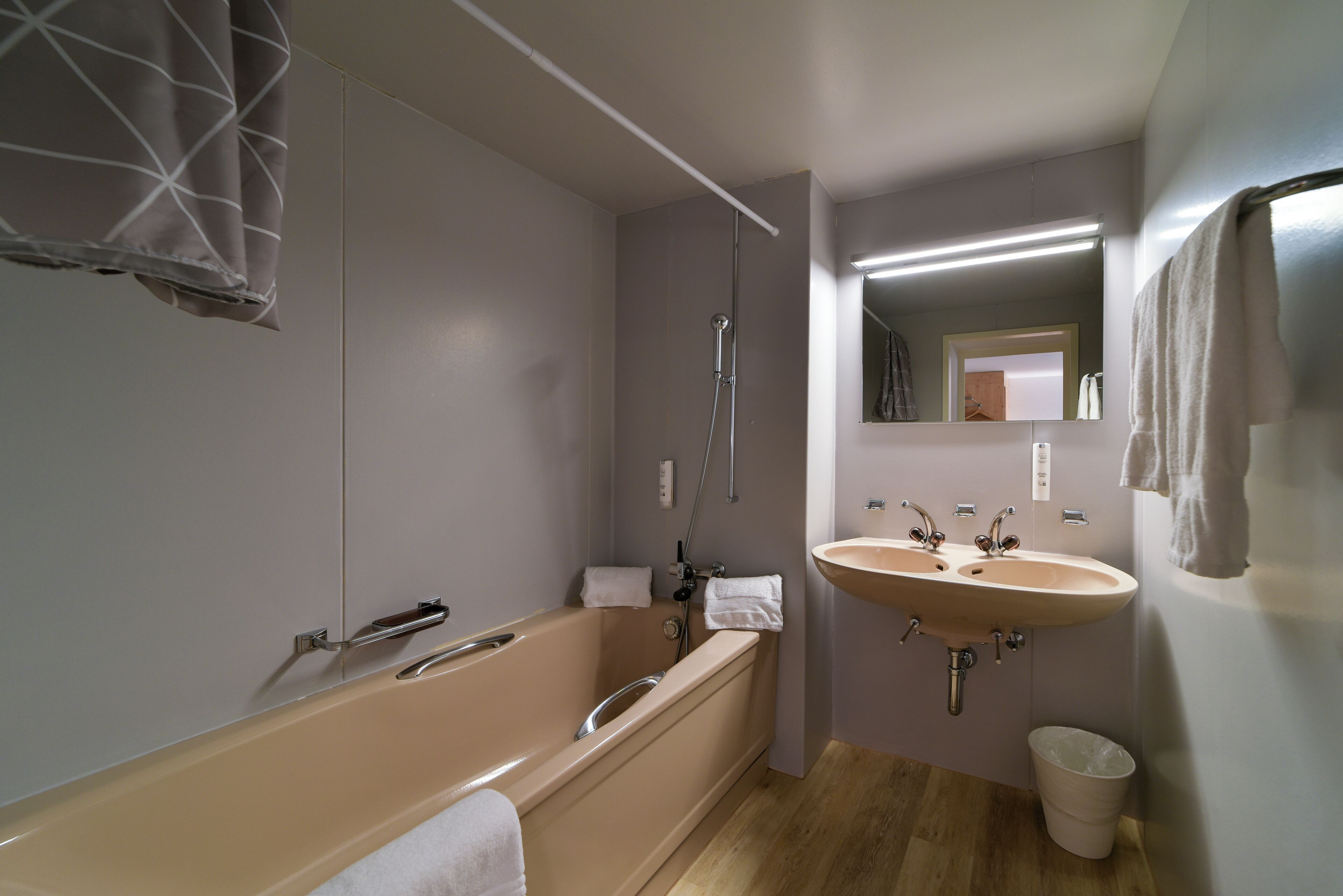 Un baño moderno con bañera, dos lavabos, un espejo y un perchero para toallas.