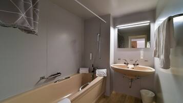 Un baño moderno con bañera, dos lavabos, un espejo y un perchero para toallas.