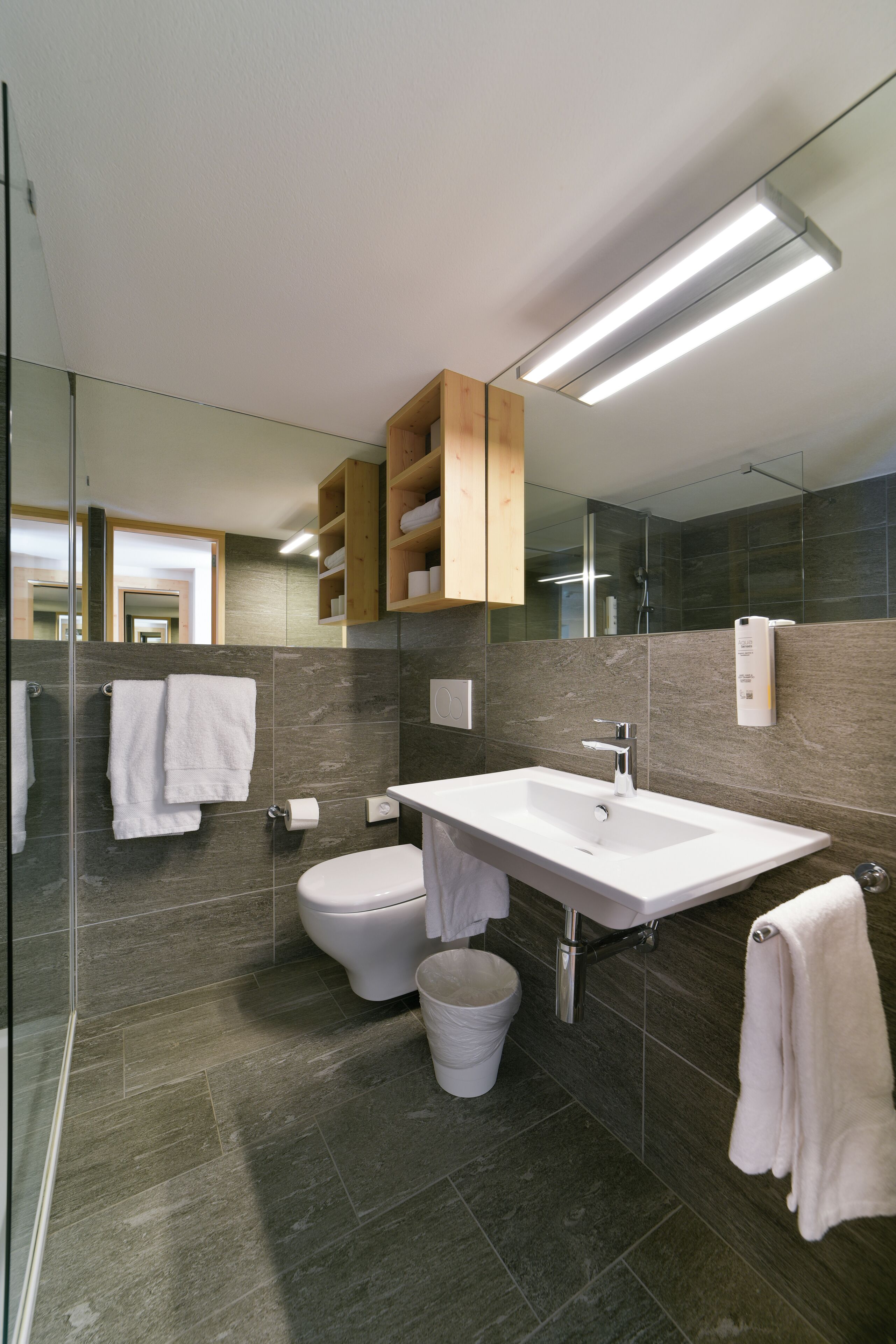 A modern bathroom with a glass shower enclosure, a white sink, and a toilet.