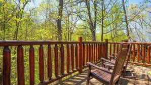 A wooden deck with a railing and two rocking chairs. - SkiView Hilltop: Honeymoon, Hot Tub, Wifi, Wooded View, Great Location! (Sevierville)