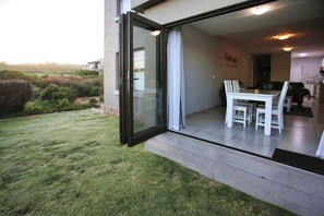 Una casa moderna con un ventanal de vidrio que da a un comedor con una mesa y sillas.