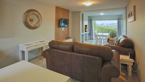 A modern living room with a brown leather sofa, a white coffee table, and a TV mounted on the wall. - Francolin's Nest, Langebaan, 4-sleeper (Langebaan)