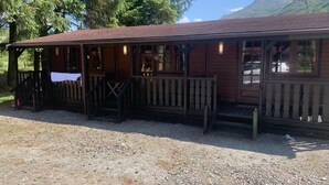 A wooden building with a porch, steps, and a gravel ground. - Double Room, Crianlarich, whw (Crianlarich)