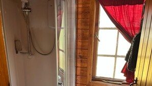 A wooden cabin bathroom with a glass-enclosed shower, a toilet, and a window with a red curtain. - Double Room, Crianlarich, whw (Crianlarich)