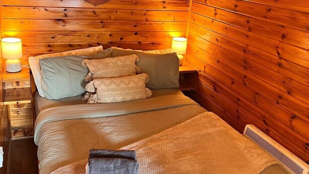 A cozy wooden cabin room with a bed, two bedside lamps, and a mounted animal head on the wall. - Double Room, Crianlarich, whw (Crianlarich)