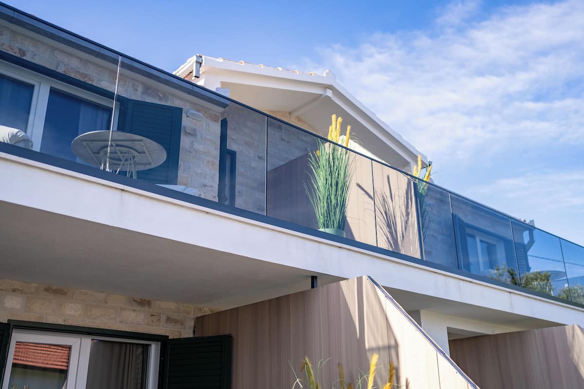 A modern building with a glass balcony, stone facade, and a satellite dish.