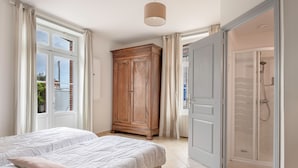 Un dormitorio con dos camas, un armario y un baño con ducha.