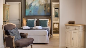 A bedroom with a bed, a chair, a dresser, and a painting on the wall. - Cloître des Augustins 5 étoiles, Spa & Fitness (Avignon)