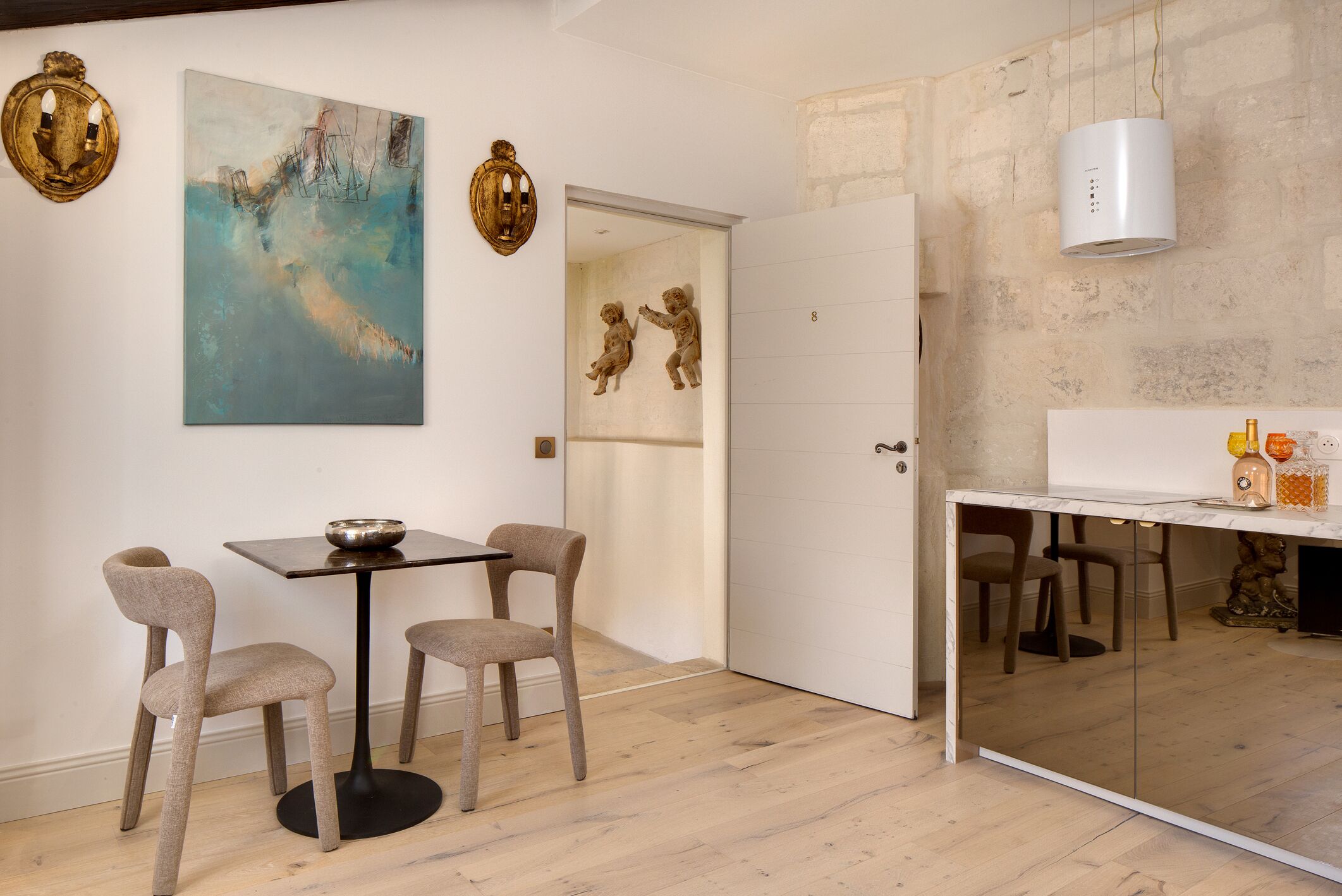 Un espace de salle à manger moderne, avec une table et des chaises, un tableau au mur et un élément décoratif mural.