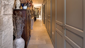 A hallway with stone walls, a wooden cabinet, and a large vase with dried flowers. - Cloître des Augustins 5 étoiles, Spa & Fitness (Avignon)
