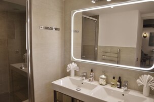 A modern bathroom with a large mirror, a sink, and a shower area.