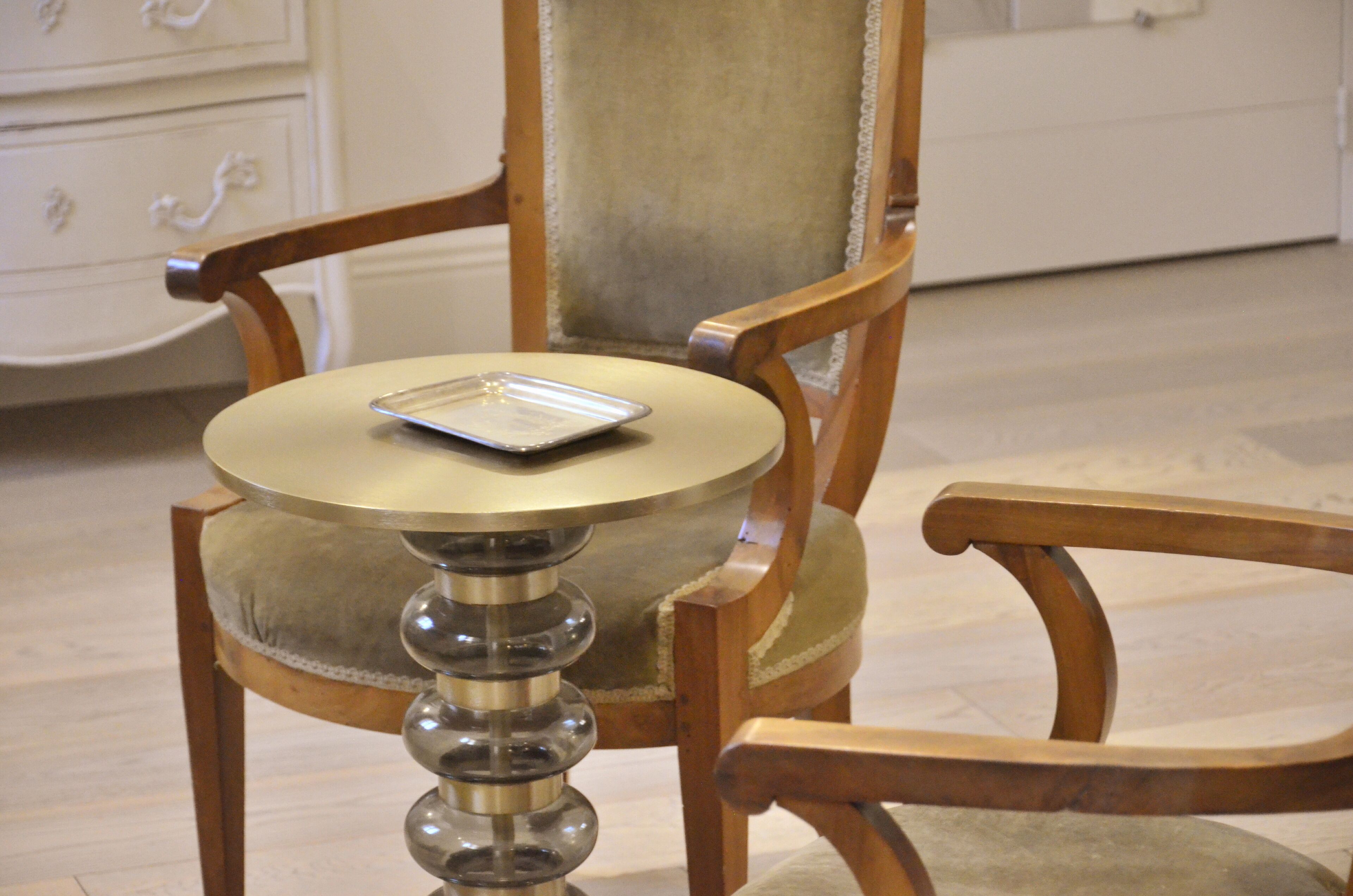 A wooden chair with a cushioned seat and a small round table with a tray.