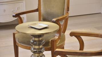 A wooden chair with a cushioned seat and a small round table with a tray.
