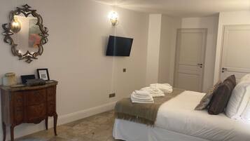 Un dormitorio con cama, cómoda, espejo, televisor montado en la pared y una puerta.