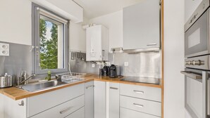 Une cuisine moderne dotée d’une fenêtre, d’appareils électroménagers en acier inoxydable et de meubles blancs.