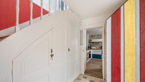 A hallway with white doors, a staircase with white balusters, and a kitchen area with a stone backsplash. - Close to port & beaches - Terrace - House for 5 (Pornic)
