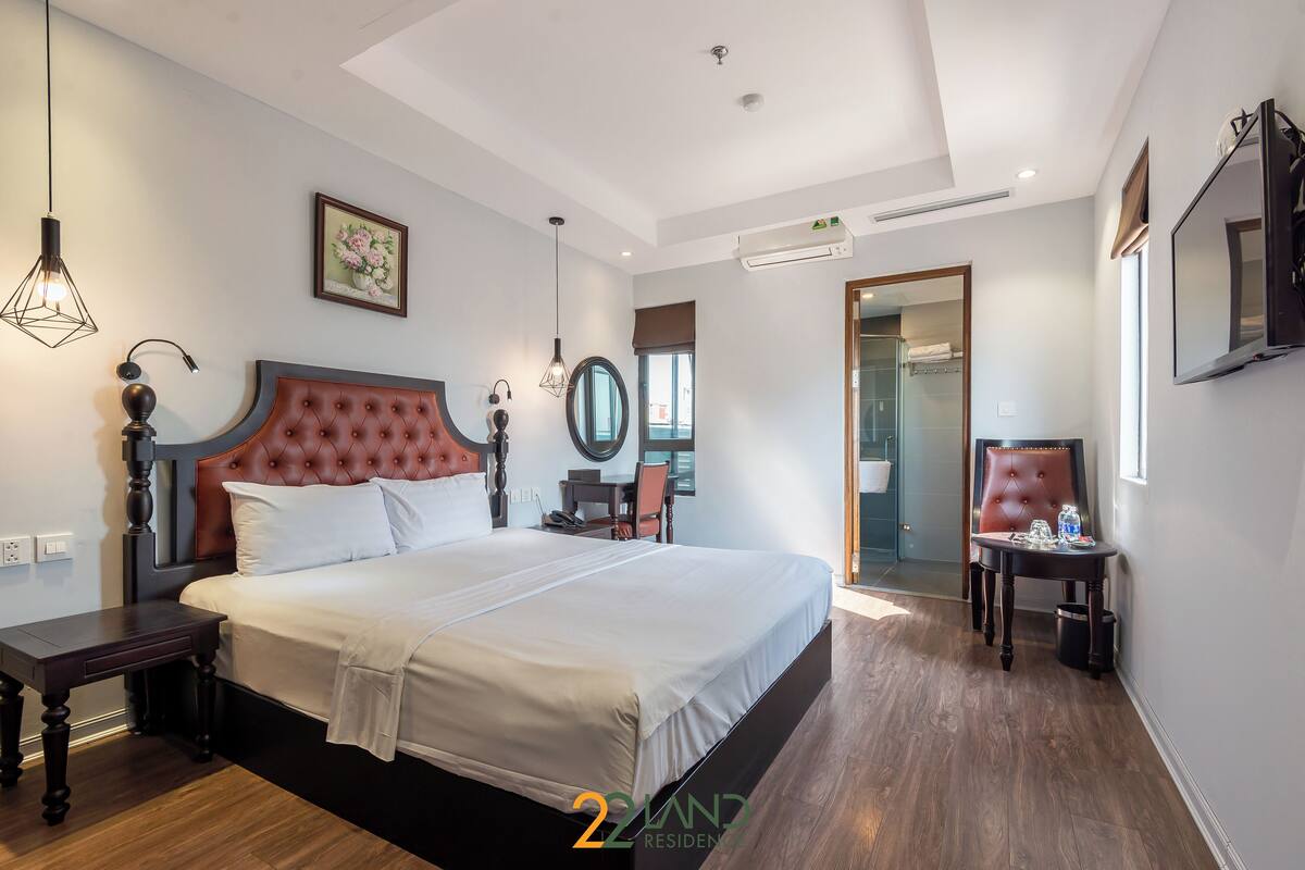 A modern hotel room with a large bed, a desk, a chair, and a television.