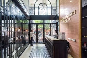 Un espace d’accueil au design moderne, comprenant un comptoir de réception, une porte en verre décorative et une enseigne indiquant l’hôtel Zeland Residence.
