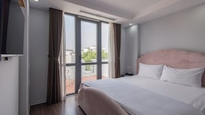 A hotel room with a large bed, a sliding glass door to an outdoor area, and a view of the cityscape.