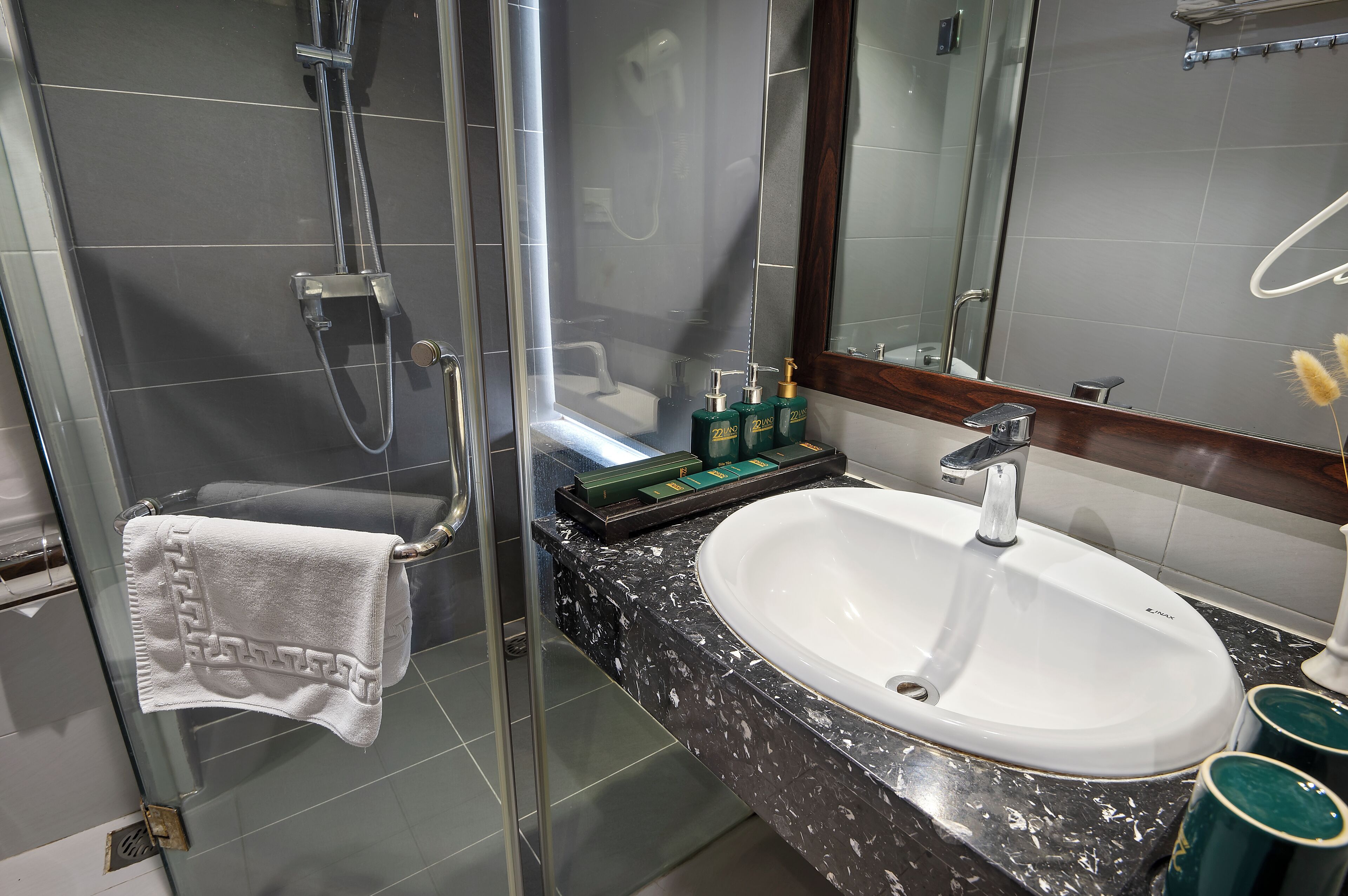 A modern bathroom with a glass-enclosed shower, a white sink, and a large mirror.