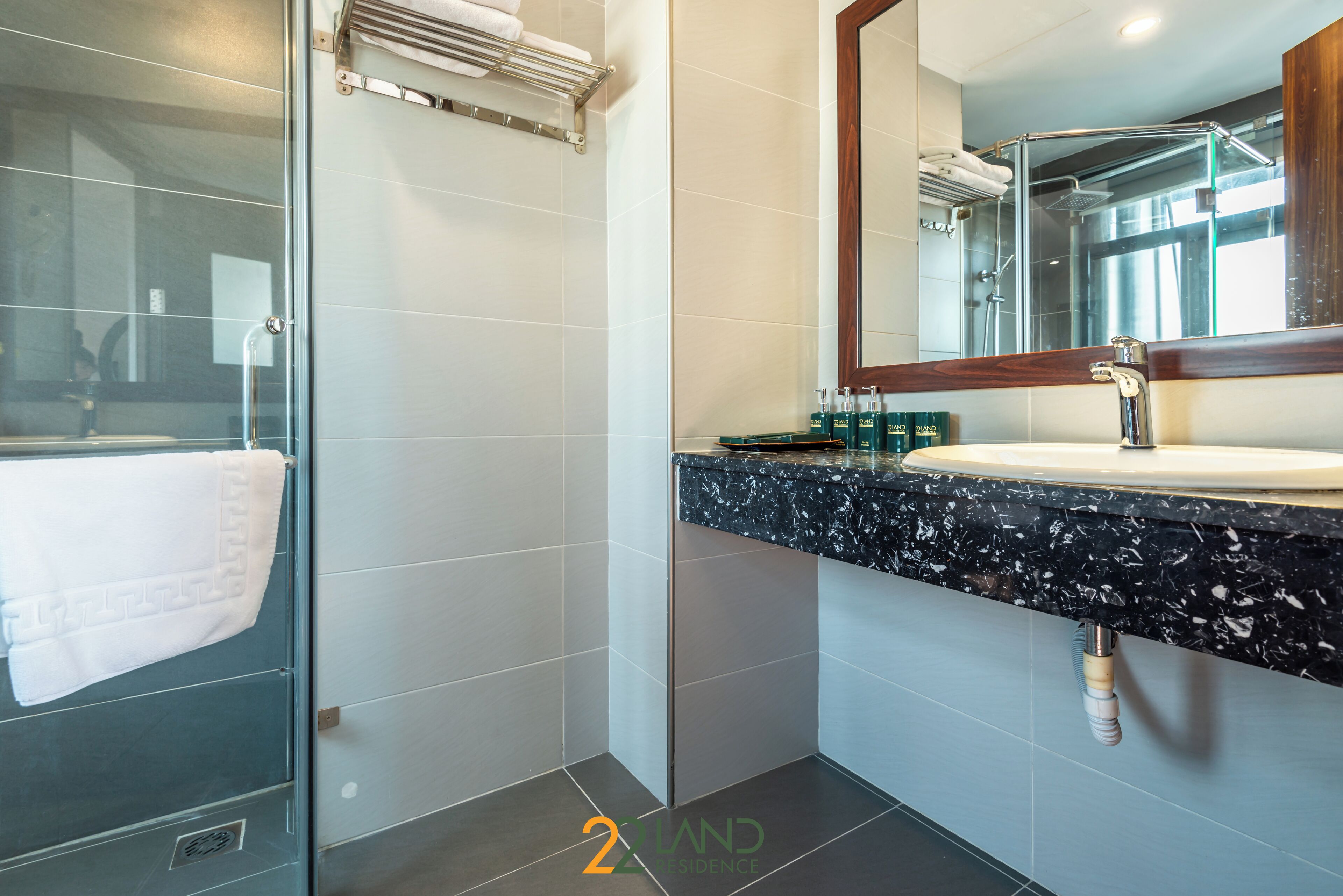 A modern bathroom with a glass shower enclosure, a marble countertop sink, and a large mirror.