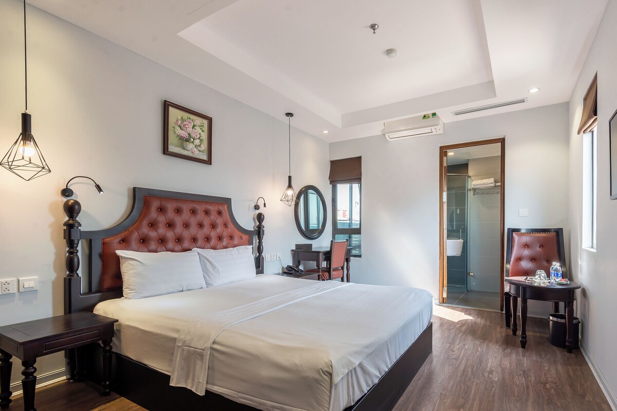 A modern hotel room with a large bed, a desk, a chair, and a television.