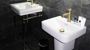 A modern bathroom with two sinks, a large mirror, and a black trash bin.