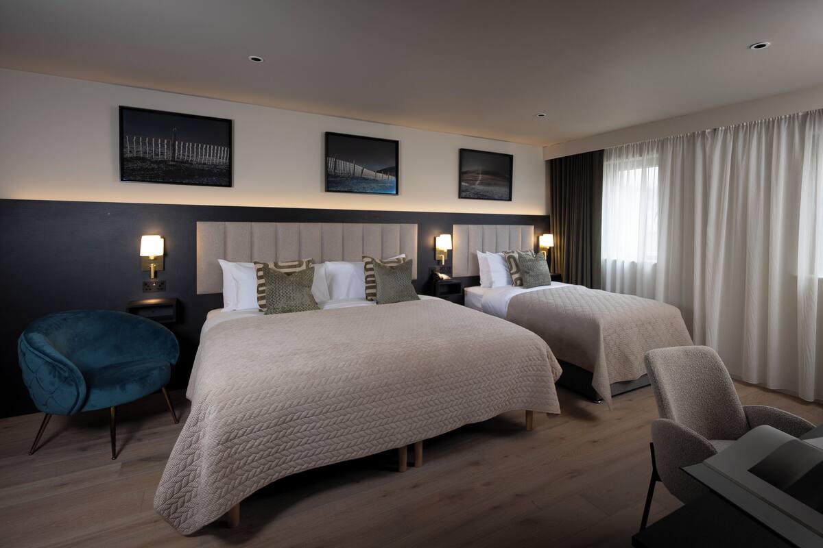 Ein Hotelzimmer mit zwei Betten, einem Schreibtisch, einem Stuhl und Blick ins Freie.