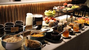 A buffet with various food items and containers, including bowls of cereal, fruits, and condiments.