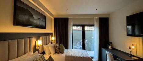A hotel room with two beds, a desk, a TV, and a large window with a view of the outside.