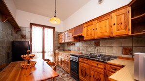 A kitchen with wooden cabinets, a stove, and a sink. - LA VILLETTA DEL NONNO BORTOLO (Castello)