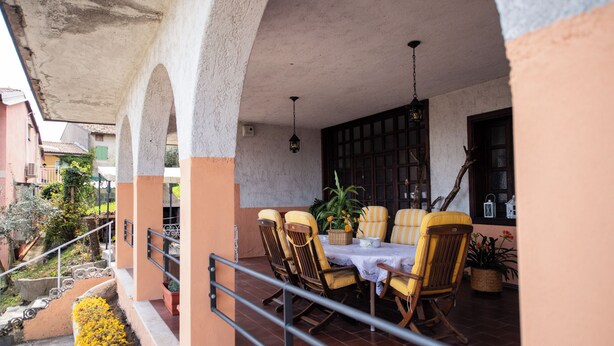 A covered outdoor dining area with a table and chairs, a hanging lantern, and a view of the street. - LA VILLETTA DEL NONNO BORTOLO (Castello)