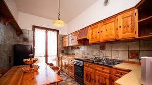 A kitchen with wooden cabinets, a stove, and a sink. - La Villetta del Nonno Bortolo (Castello)