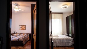 Two bedrooms with wooden floors, one with a patterned bedspread and a ceiling fan, and the other with a plain bedspread and a bedside table. - La Villetta del Nonno Bortolo (Castello)