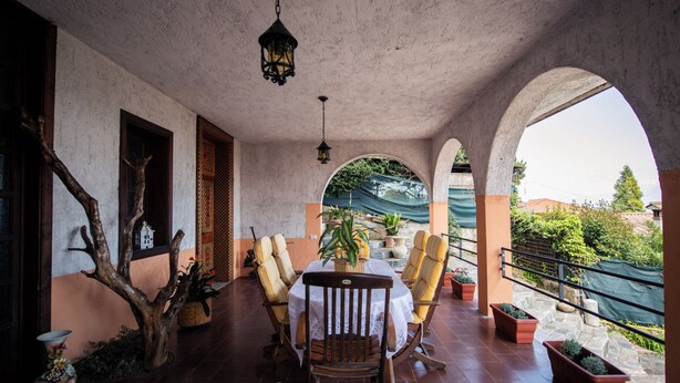 A covered patio with a table and chairs, potted plants, and a view of the surrounding area. - La Villetta del Nonno Bortolo (Castello)