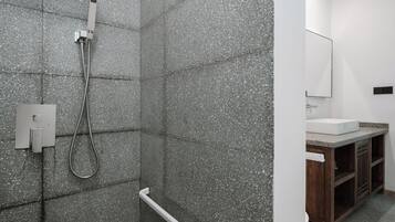 Un baño con ducha, lavamanos y espejo.