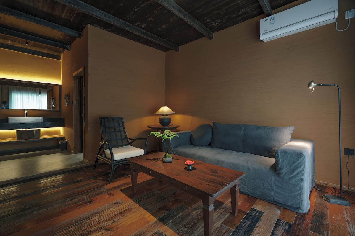 Un salon moderne avec un canapé, une table basse en bois, un fauteuil et une lampe.