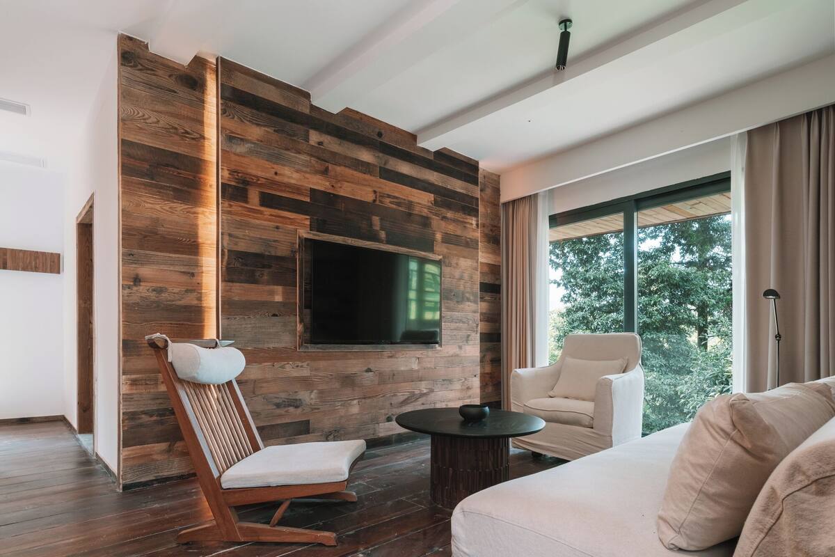 Un salon moderne avec un mur en bois, un téléviseur à écran plat, un canapé, un fauteuil et une table basse.