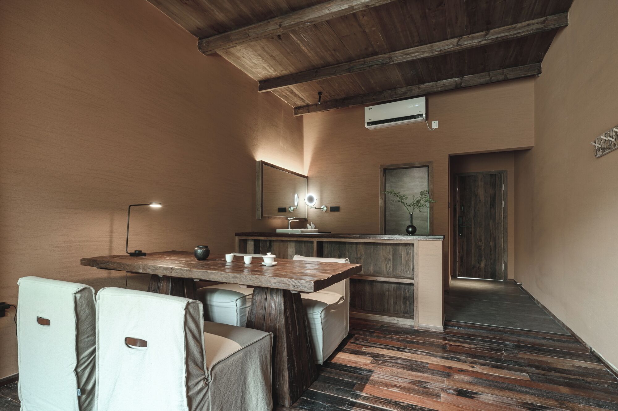 Una cocina pequeña con una mesa de madera, sillas y un lavamanos.