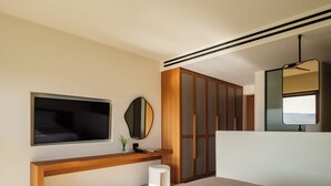 Un dormitorio moderno con una cama grande, un televisor montado en la pared, una consola de madera, un espejo y un armario con puertas correderas.