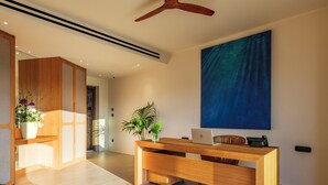 Un interior moderno con un mostrador de recepción de madera, una computadora portátil y un cuadro abstracto grande en la pared.