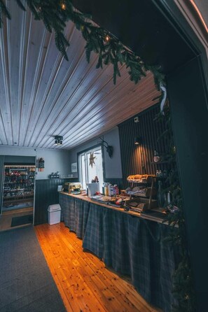 Une pièce chaleureuse avec un plancher en bois, un coin bar doté d’un comptoir, une fenêtre décorée d’une étoile et une étagère contenant divers objets.