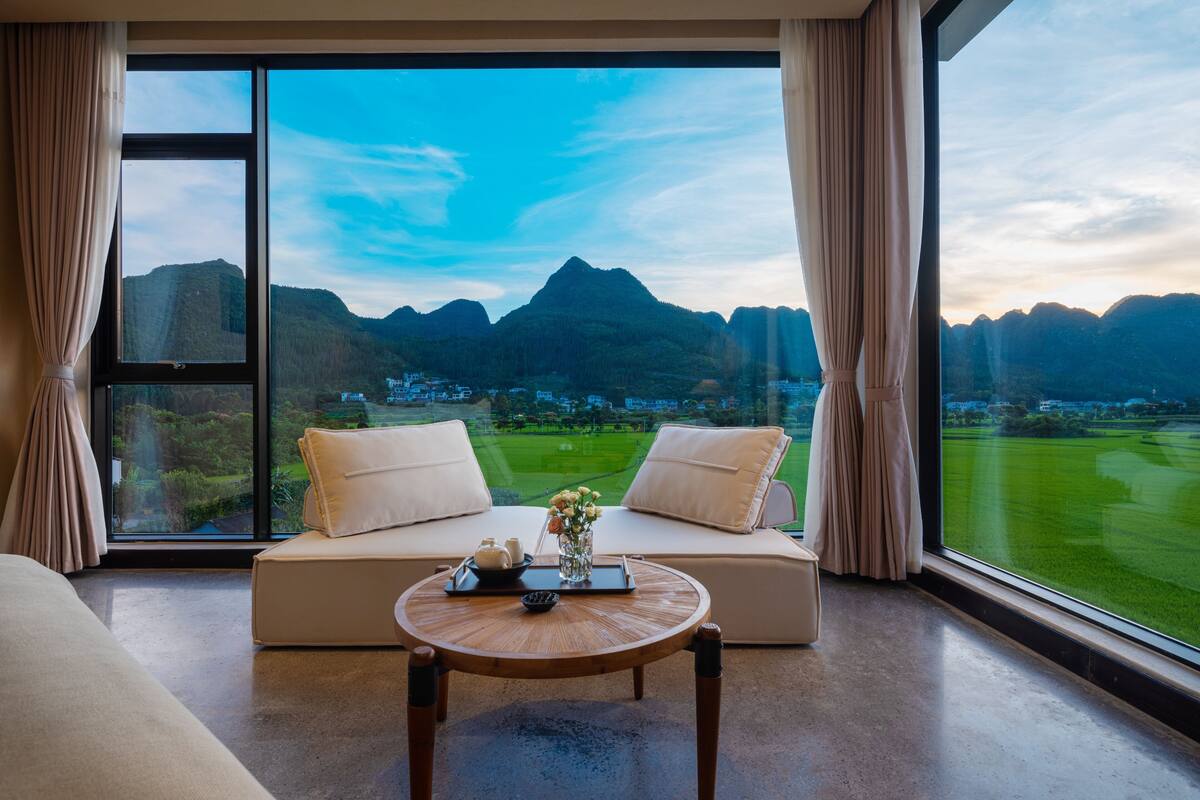 Ein modernes Zimmer mit großem Fenster und Blick auf Berge sowie einen Golfplatz.