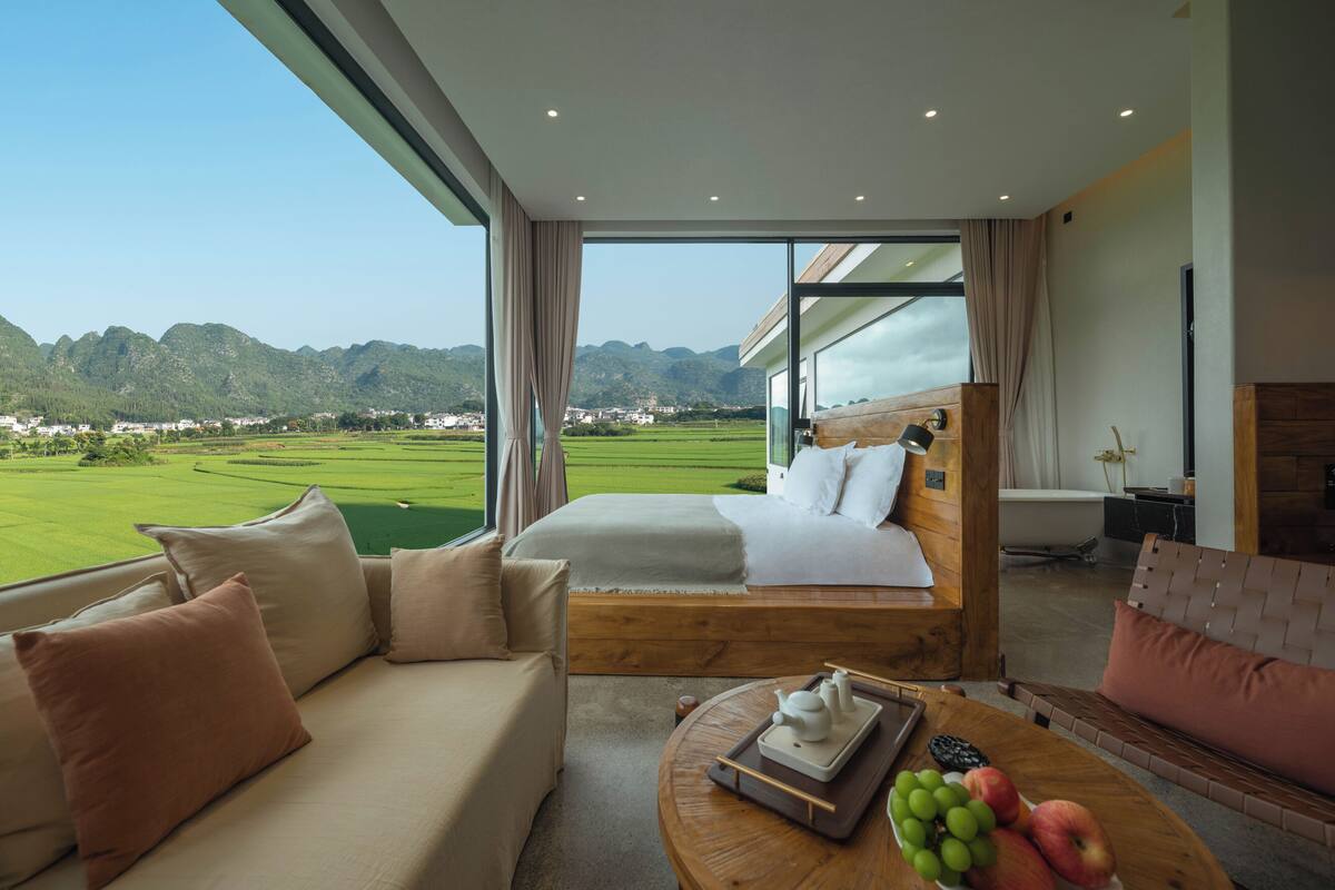 Ein modernes Schlafzimmer mit einem großen Bett, einer Couch und einem Couchtisch mit Obst.